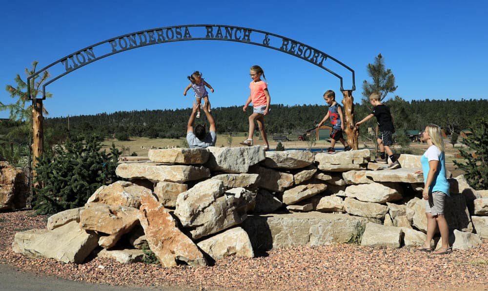 Children play on rocks near a sign for "Ponderosa Ranch & Resort."
