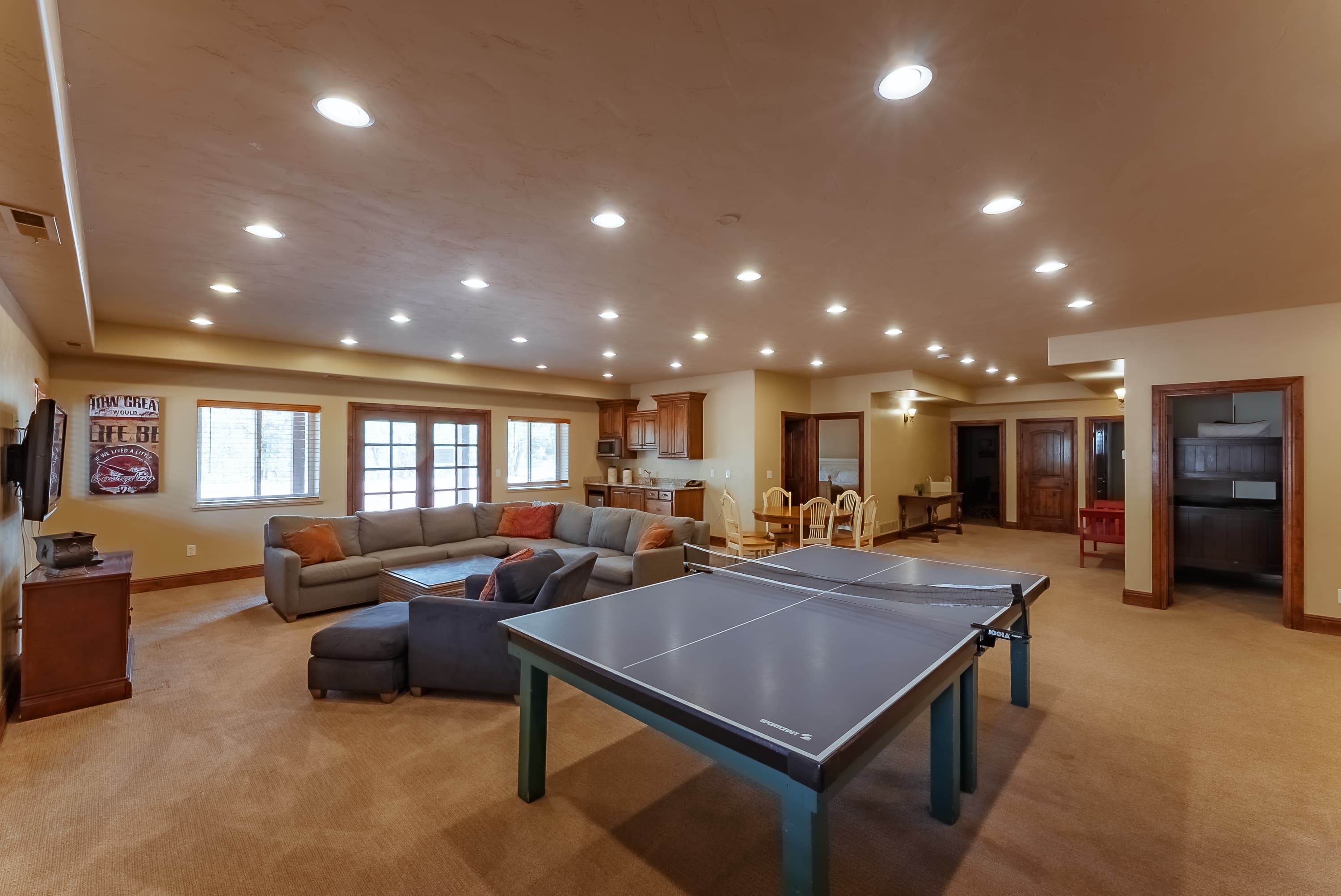 A spacious recreational room featuring a ping pong table, cozy seating area, and a well-equipped kitchen.