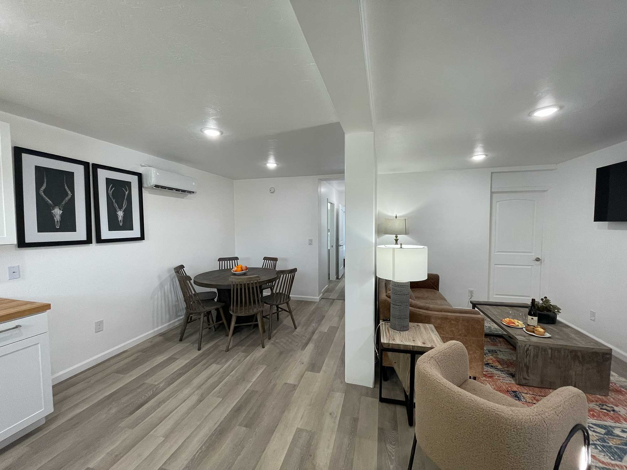 A modern living space featuring a dining area with a table and chairs, a cozy seating arrangement, and minimalist decor in neutral tones.