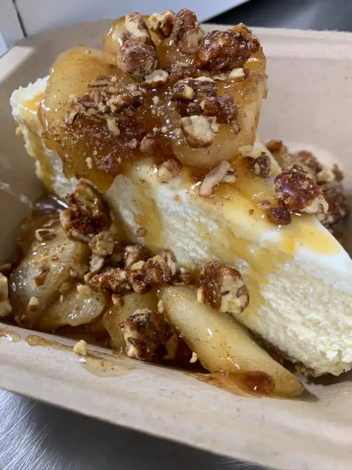 A slice of cheesecake topped with caramelized apples and crunchy pecans.