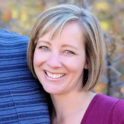 A smiling woman with short hair stands close to a person in a striped shirt.