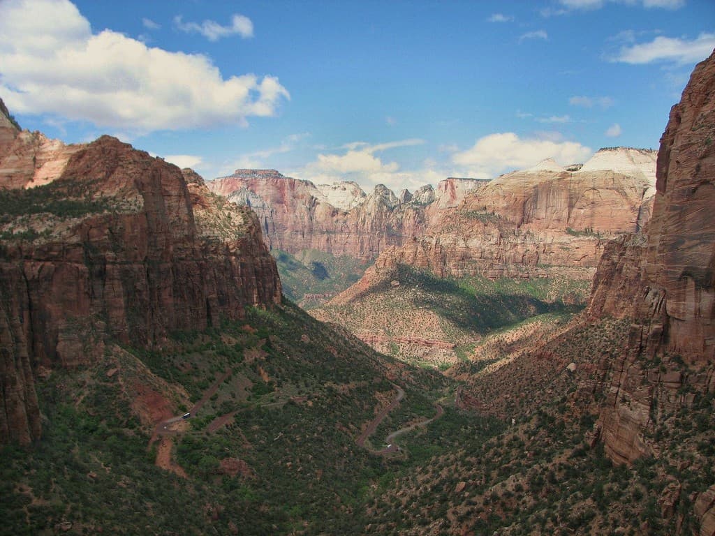 A stunning view of Zion National Park's red rock canyon under a blue sky with scattered clouds.