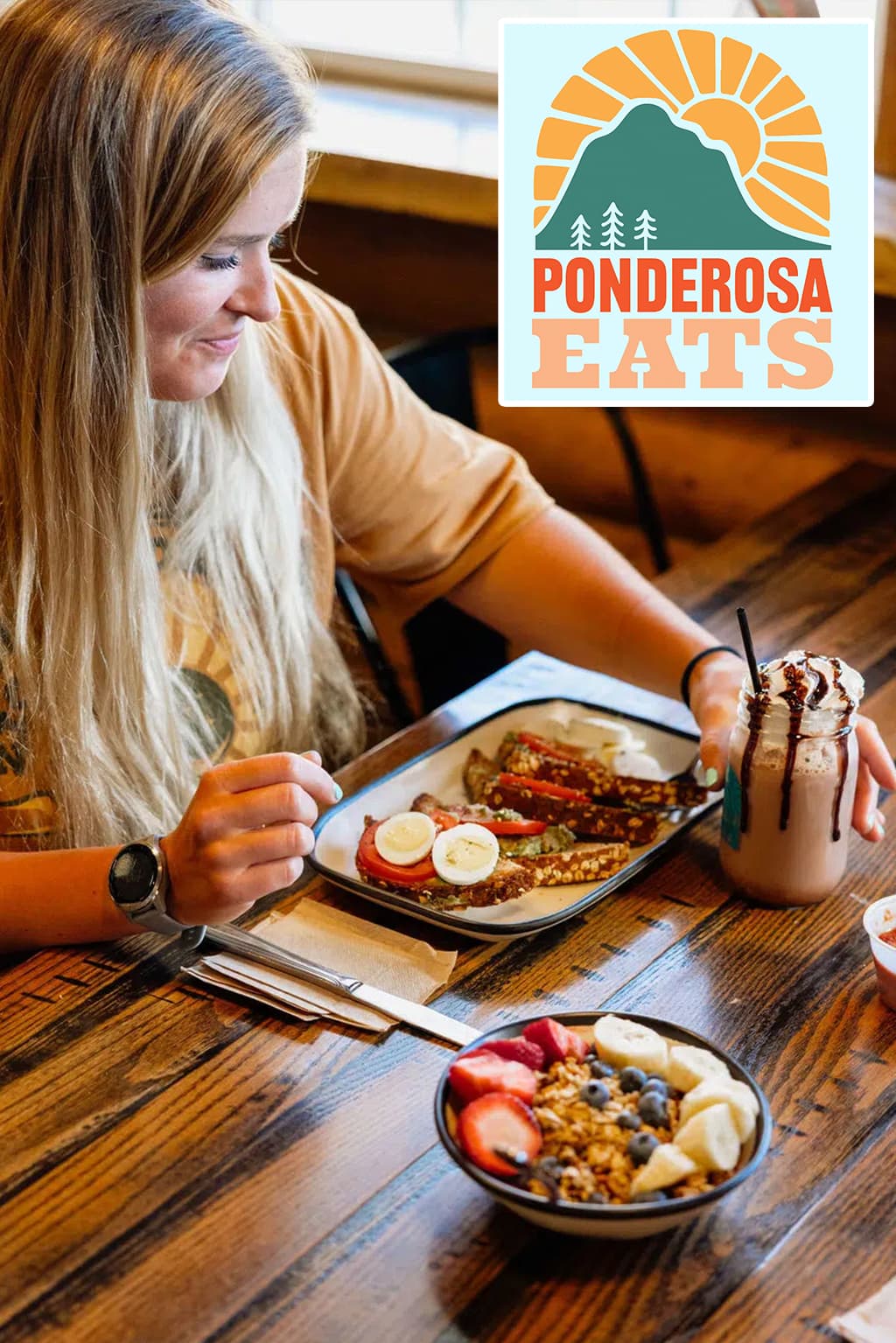 A woman enjoying a meal featuring pancakes and fruit, with a beverage on the table at Ponderosa Eats.