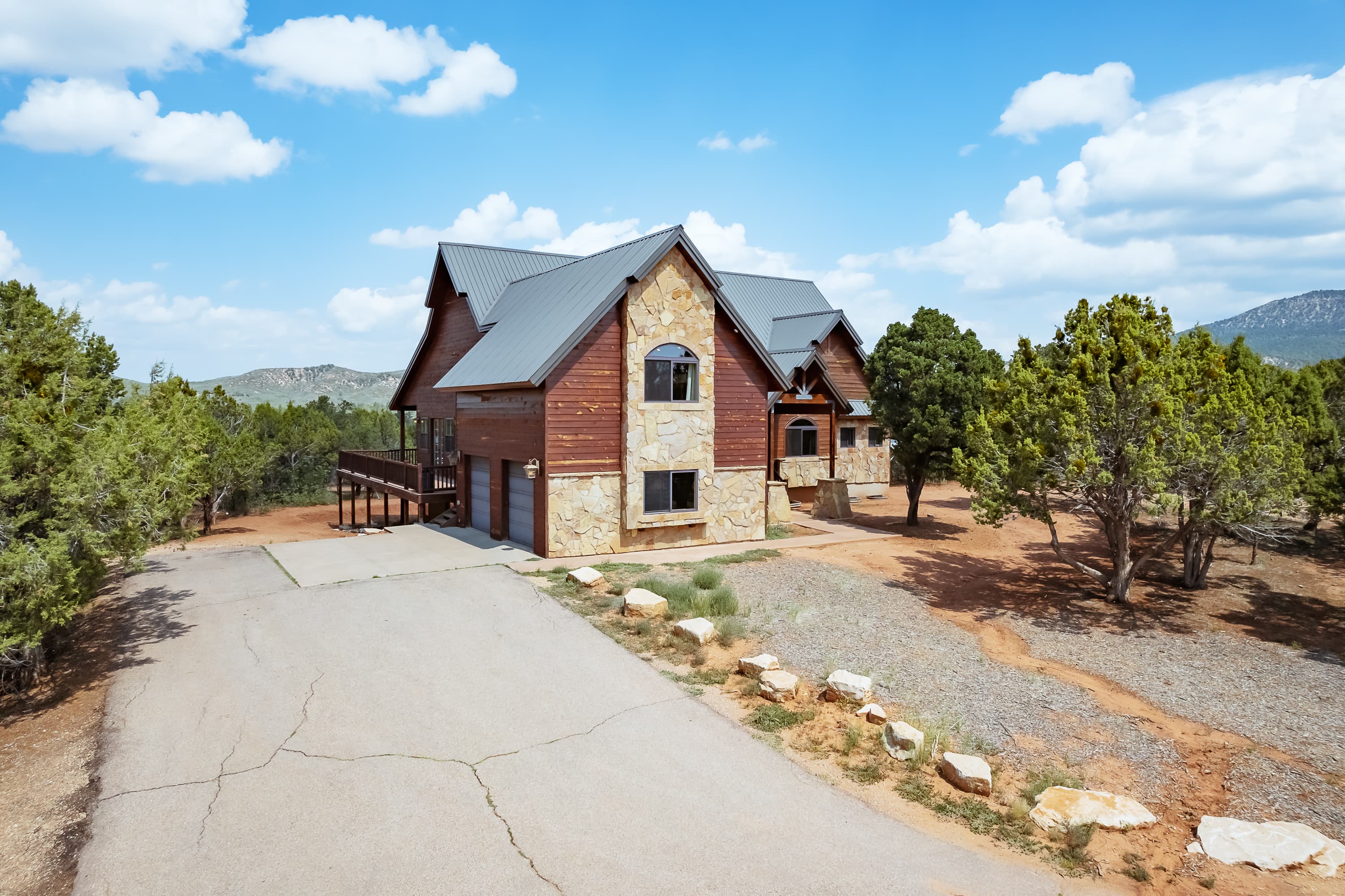 A large rustic house made of stone and wood surrounded by trees under a blue sky.