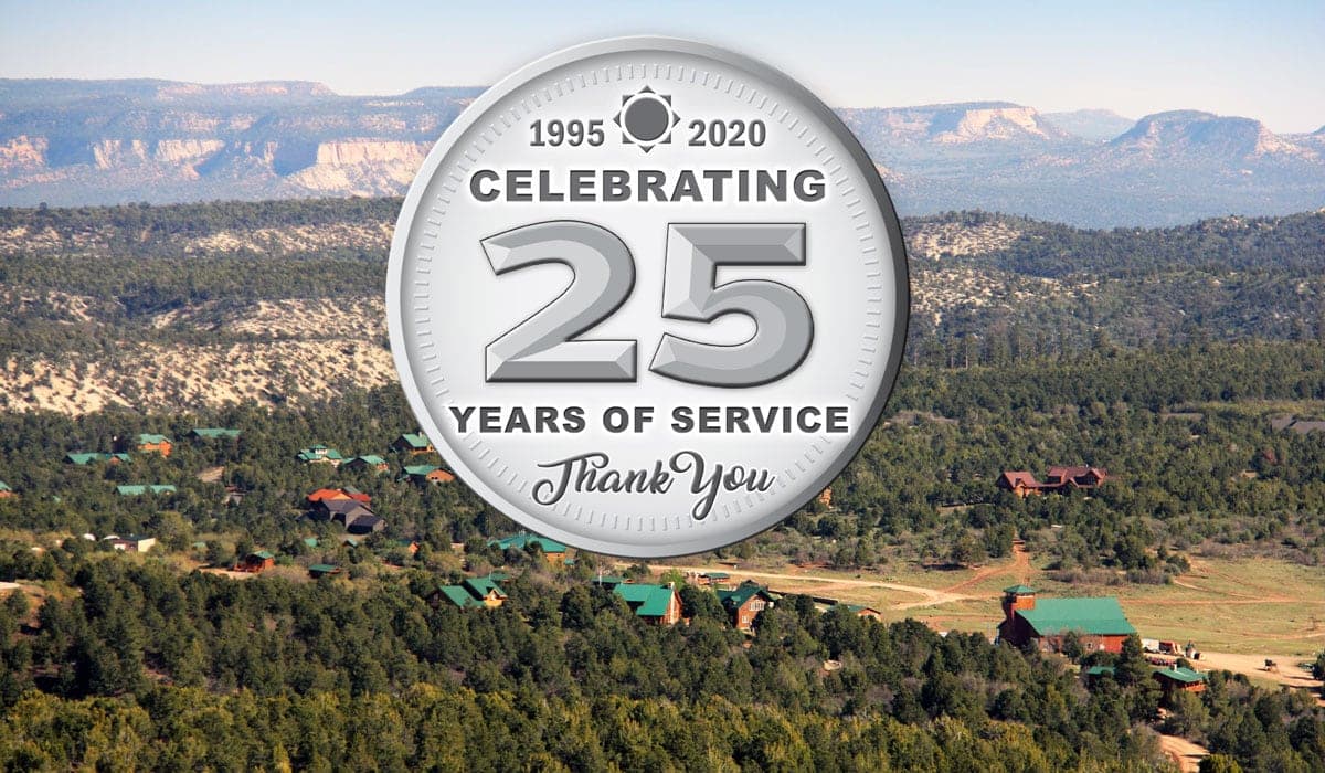A silver medal commemorating 25 years of service, set against a scenic mountainous landscape.