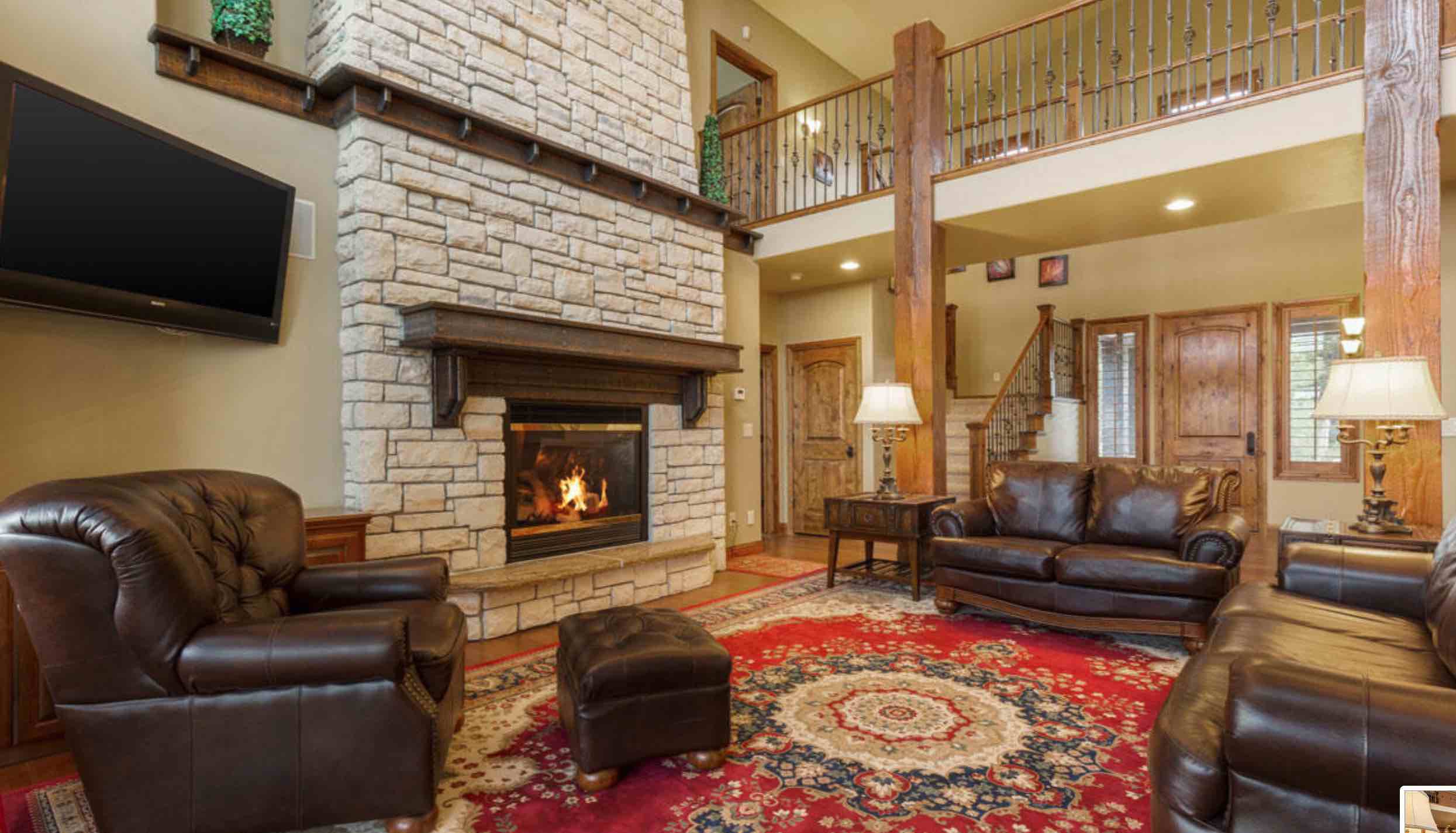 Cozy living room with a stone fireplace, leather sofas, and hardwood accents.
