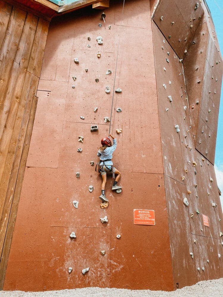 A person in a helmet climbs a vertical rock wall with various holds.