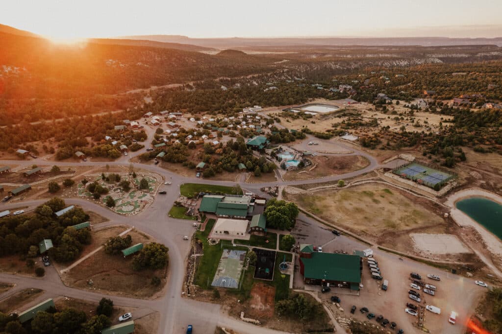 Aerial view of a rural community at sunset, showcasing buildings, roads, and surrounding landscape.
