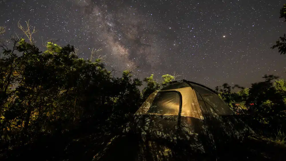 A tent sits under a starry sky filled with the Milky Way.
