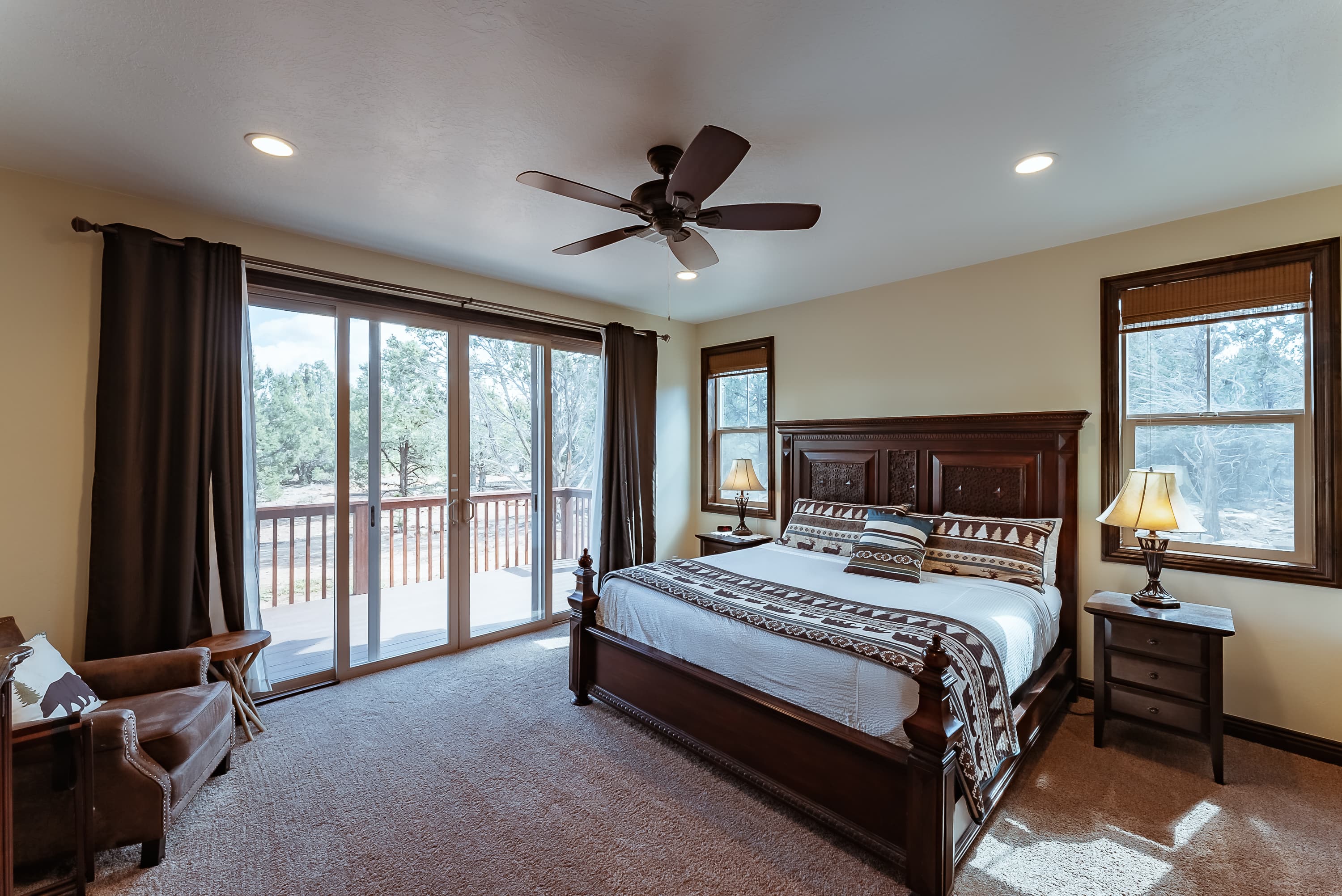A cozy bedroom featuring a wooden bed, two lamps, and large sliding doors opening to a deck.