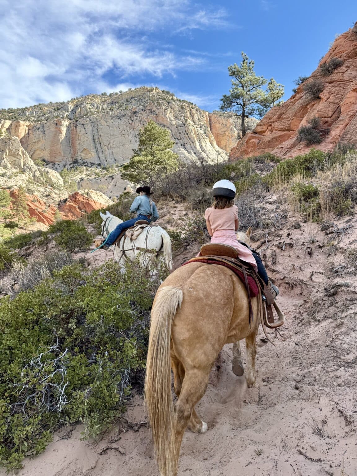 Two people horseback riding in a Utah canyon