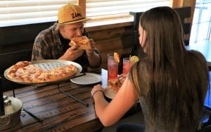 Man with Zion hat eating pizza with girlfriend at Zion Ponderosa dining near Zion National Park