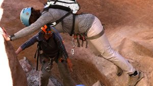 a canyoneering guide helps a tourist safely navigate a slot canyon near zion national park