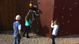 a mother helps her child climb a man made rock wall at zion ponderosa ranch while a woman takes a photo