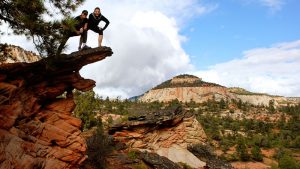 two friends pose on top of a rock formation for a picture near Zion national park