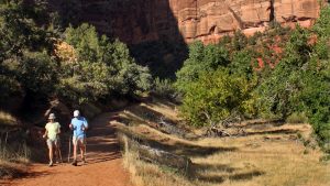 an older couple hikes an easy trail near the tall walls of Zion National Park