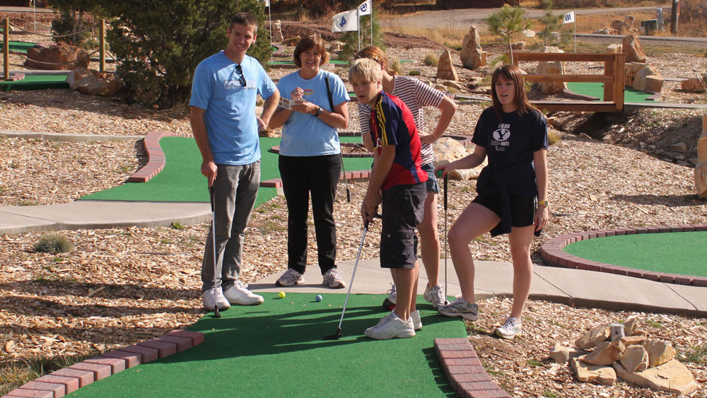 A group of teenagers and their mother are beginning to play mini golf