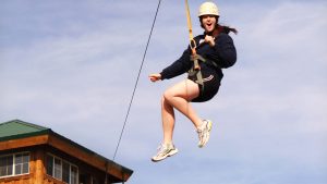 a woman wearing a helmet is excited while riding riding a zipline at Zion Ponderosa Ranch
