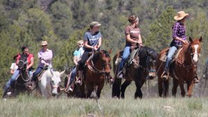 A group of tourists riding horses follow a tour guide at Zion Ponderosa Ranch