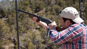a man shoots a shotgun into the wilderness