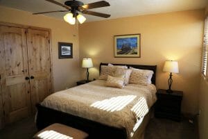 A queen bed is neatly made inside a clean room of a vacation home at Zion Ponderosa Ranch