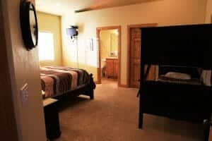 A neatly made full sized bed and a set of buck beds with a mini TV inside of a vacation home at Zion Ponderosa Ranch