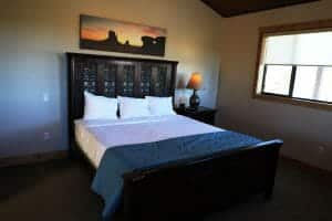 a neatly made queen sized bed inside of a vacation home at Zion Ponderosa Ranch