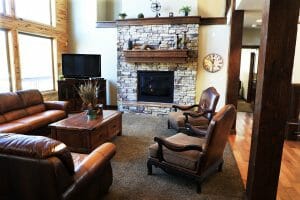 a comfortable living room with a TV and a stone fireplace inside of a vacation home at Zion Ponderosa Ranch