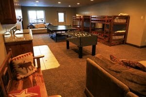 a cozy couch, 2 sets of bunk beds, and a game room inside of a vacation home at Zion Ponderosa Ranch