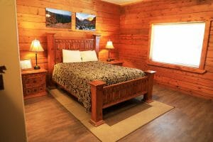 a neatly made bed inside a wood walled bedroom at a vacation home at Zion Ponderosa Ranch