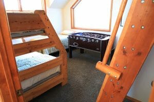 a kids room with 2 neatly made bunk beds and a twin sized bed and a foosball table in a vacation home near Zion national park