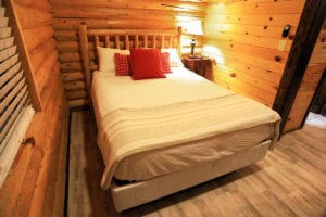 a neatly made queen sized bed inside a log cabin suite at Zion Ponderosa Ranch