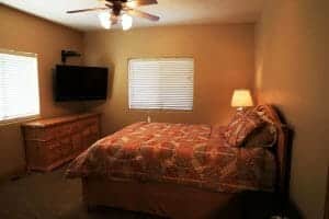 a bedroom with a neatly made full sized bed and a mounted TV in a vacation home at zion ponderosa ranch
