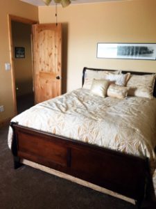 A large bed is nicely made in a clean bedroom with a wooden door