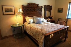A bed is neatly made in an old timey themed room