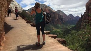 A woman poses for a photo her friend is taking on the hike to angels landing