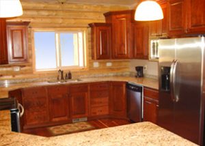 A wooden log cabin has a nice and clean kitchen with stone counter tops
