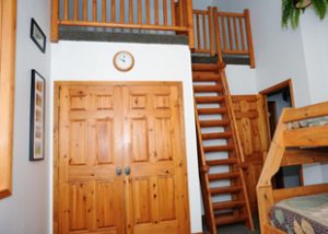 a wooden step ladder leads to a children's loft above a closet