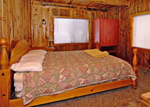 a large clean bed is made in a wood paneled room