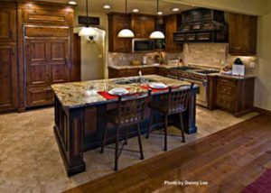 A nice and clean kitchen has dark wooden cabinets and an island with two bar seats