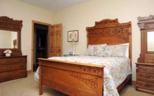 A bedroom with a clean bed and wooden nightstand and dresser.