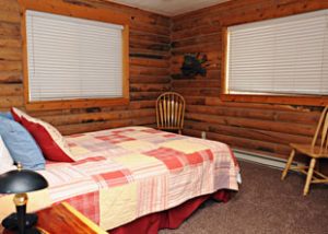 A bed is neatly made in a rustic looking cabin at Zion Ponderosa Ranch
