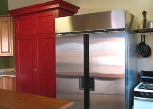 A clean kitchen has a shiny stainless steal refrigerator