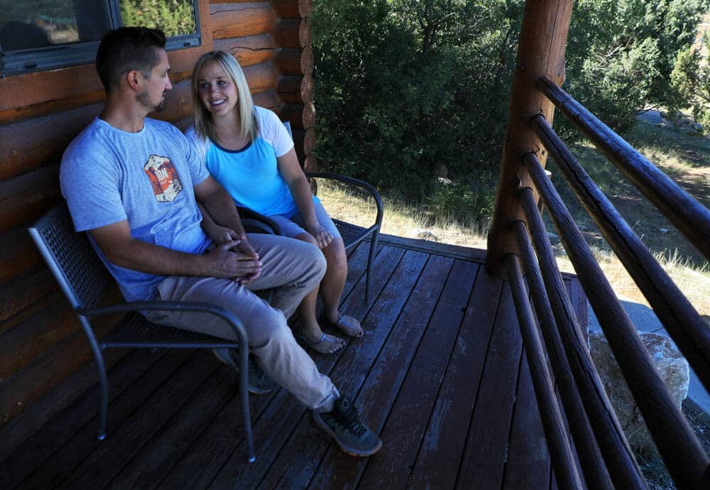 A couple sitting on the front porch of one of Zion Ponderosa’s cabins near Zion National Park