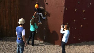 a mother helps her child climb a man made rock wall at zion ponderosa ranch while a woman takes a photo